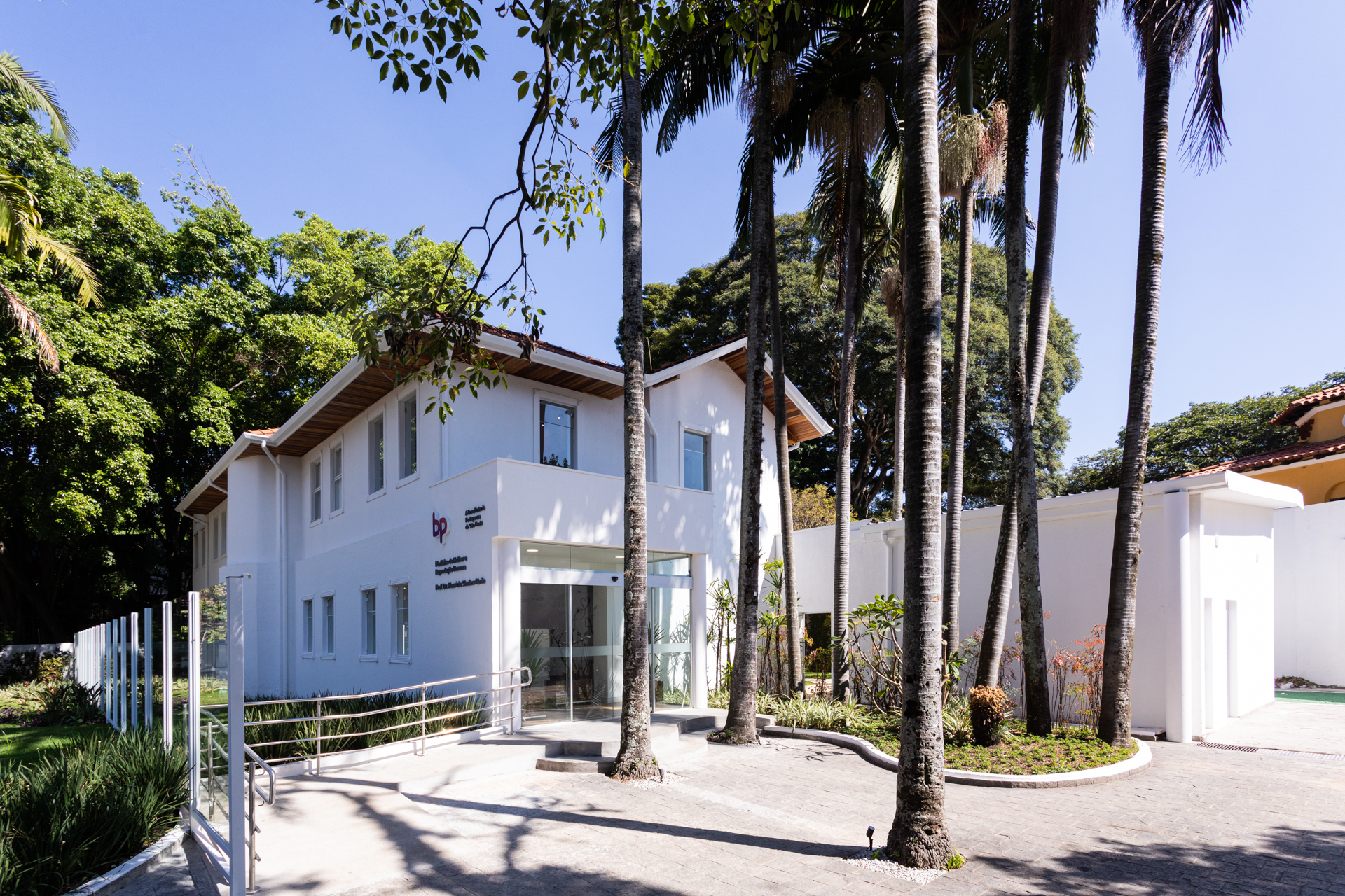 Fachada do consultório da Dra. Marina Andres em São Paulo, edifício branco moderno cercado por palmeiras